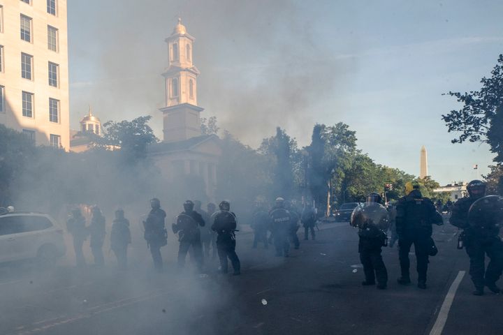 Tear gas floats in the air as a line of police moves demonstrators away from St. John's Church on Monday.