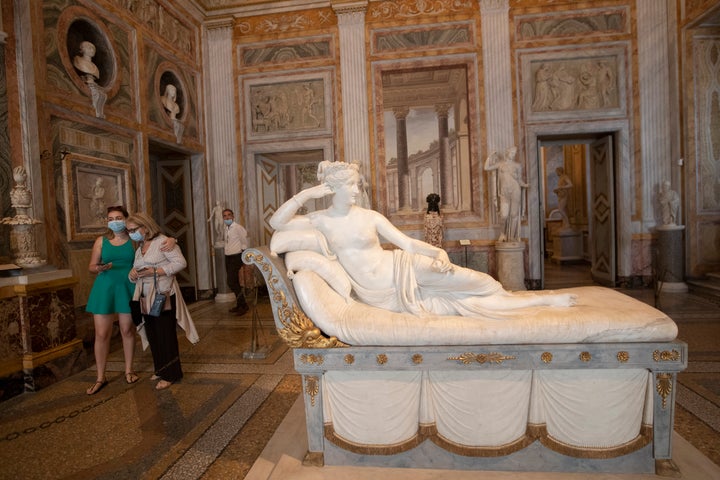 Women wearing masks to prevent the spread of COVID-19 walk past the sculpture "Pauline Bonaparte as Venus Victrix" graven by Antonio Canova between 1805 and 1808 at the Galleria Borghese art gallery, Wednesday, June 3, 2020. Italy opened regional and international borders Wednesday in the final phase of easing its long coronavirus lockdown. (AP Photo/Alessandra Tarantino)