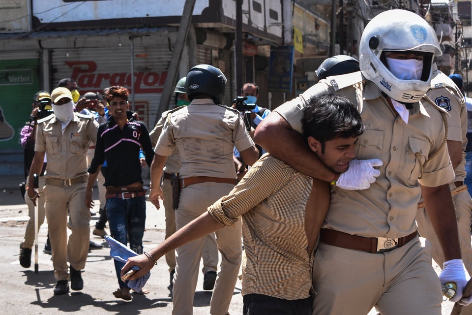 Gujarat Police personnel detain stranded migrant workers during a protest in Surat on May 4. Protesting...