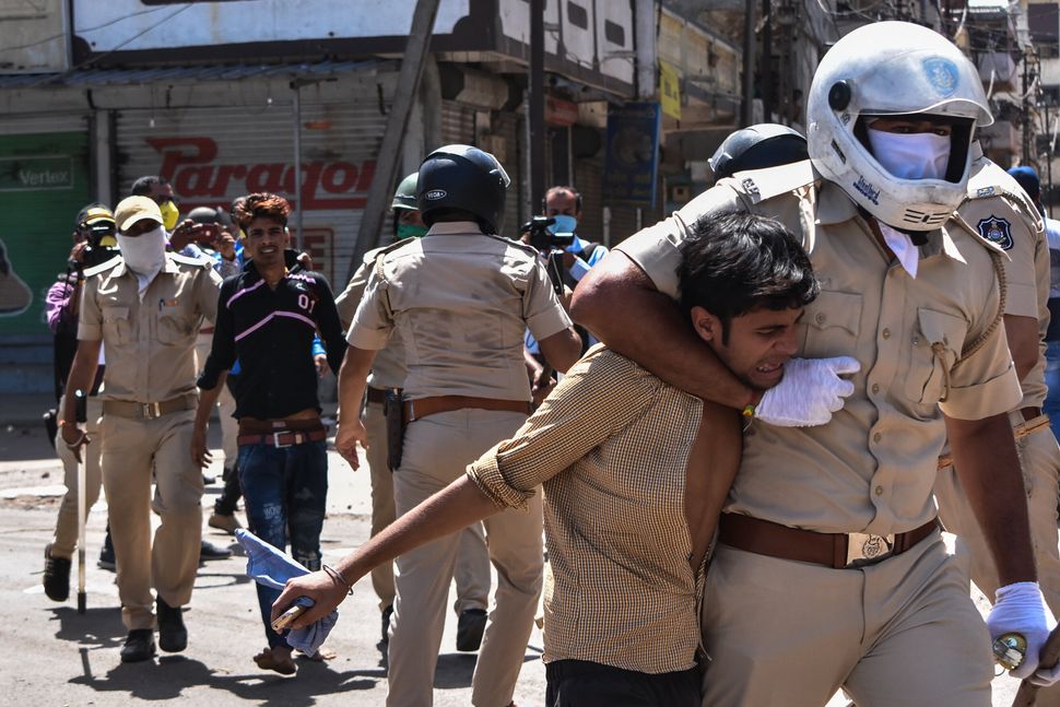 Gujarat Police personnel detain stranded migrant workers during a protest in Surat on May 4. Protesting migrant workers were demanding travel arrangements from the Gujarat state government to return to their home states. 