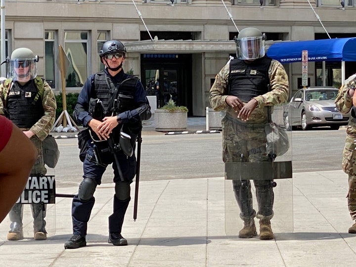 A member of federal law enforcement stands among members of the National Guard on Wednesday. Without nametags or ID on unifor