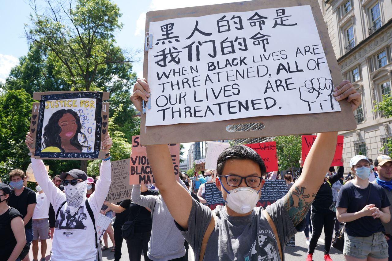 A protester holding a sign reading "Black Lives Are All Of Our Lives" in Chinese and "When Black Lives Are Threatened, All Of Our Lives Are Threatened" in English at Lafayette Square next to the White House on May 31, 2020.