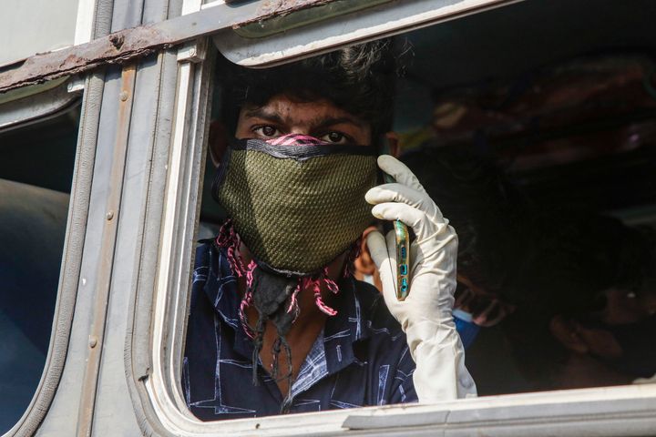 A masked Indian commuter speaks on a mobile phone as he travels in an interstate bus in Kolkata, on Wednesday, June 3, 2020.
