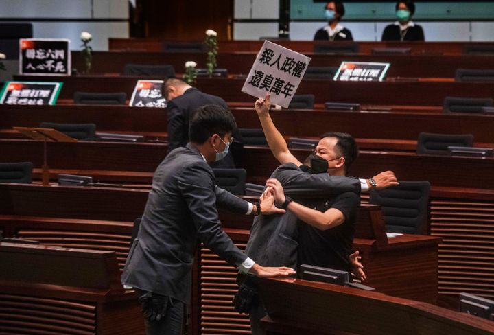 Pan-democratic legislator Chan Chi-chuen, holding a placard reading "A murderous regime stinks for ten thousand years," scuffles with security guards at the main chamber of the Legislative Council on June 4, 2020. 