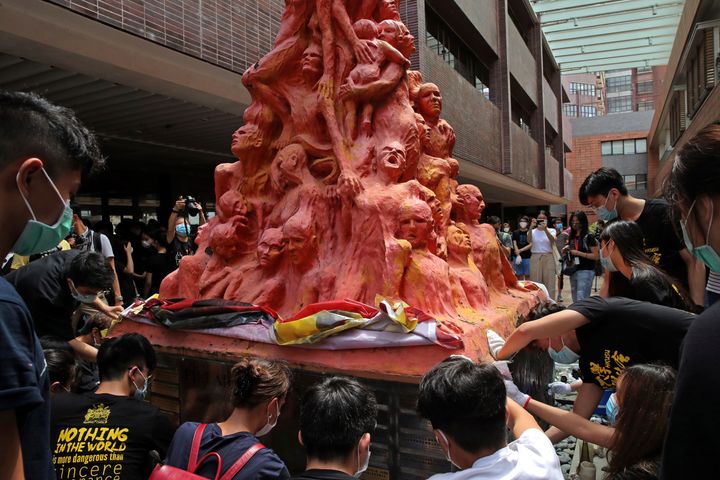 University students clean the "Pillar of Shame" statue, a memorial for those killed in the 1989 Tiananmen crackdown, at the University of Hong Kong, on June 4, 2020. 