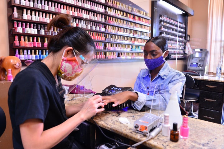 Manicure atende cliente protegida por uma tela de acrílico no Nails and Spa Salon, em Miramar, Flórida, no fim de maio.