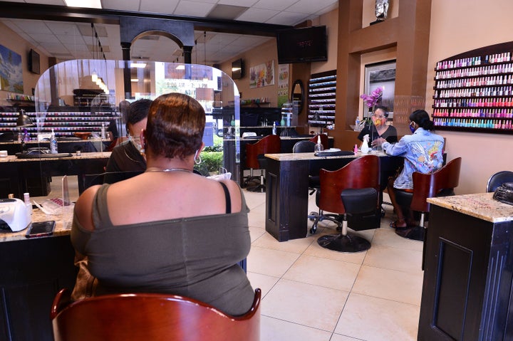 Duas manicures atendem clientes no salão Nails and Spa, em Miramar, Flórida, 20 de maio de 2020. Há um espaço entre as clientes para evitar o contato.
