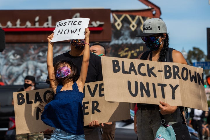 A girl jumps holding a sign while she and her family protest in the Boyle Heights neighborhood of Los Angeles on May 30.