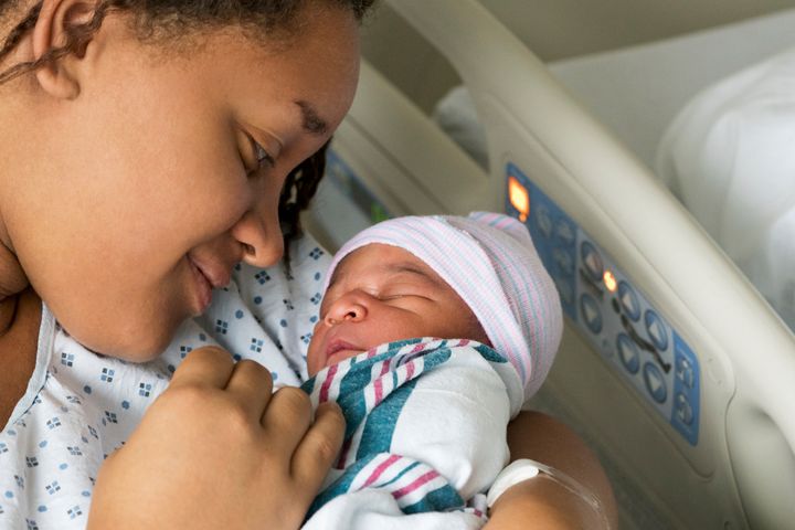 A Black mother cradles her newborn baby in the hospital.
