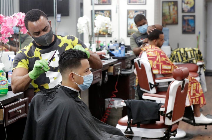 Barbers in Florida wear masks to protect against the coronavirus while at work on May 21. Personal grooming shops were allowed to open the day before, during a phased reopening of certain businesses in Miami-Dade County.