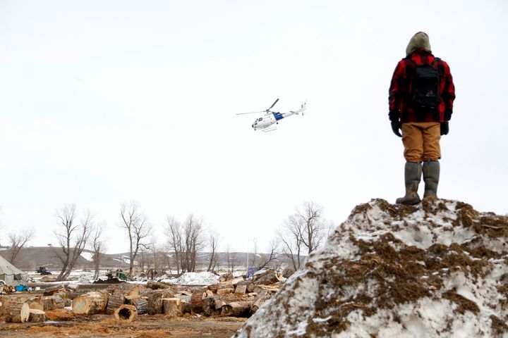 A protester watches a law enforcement helicopter circle the main opposition camp against the Dakota Access oil pipeline near Cannon Ball, North Dakota, in February 2017.
