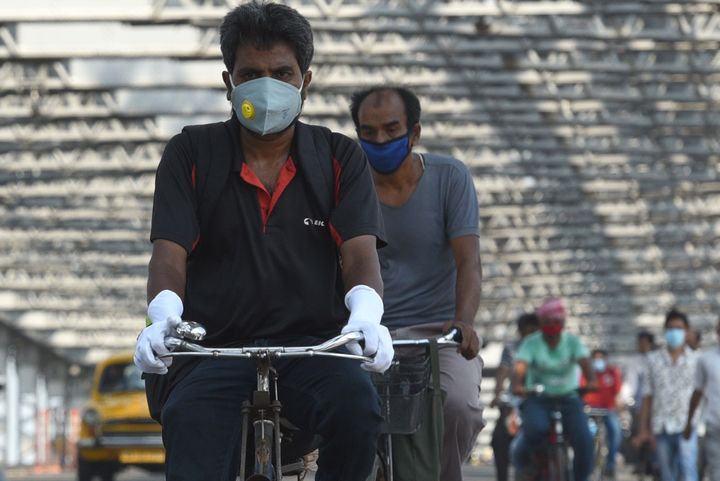 Commuters wear face masks as they cycle over Howrah Bridge at Howrah on June 3, 2020 in Kolkata.