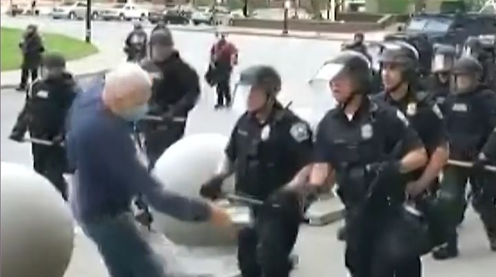 警官に押されるデモ参加者の男性