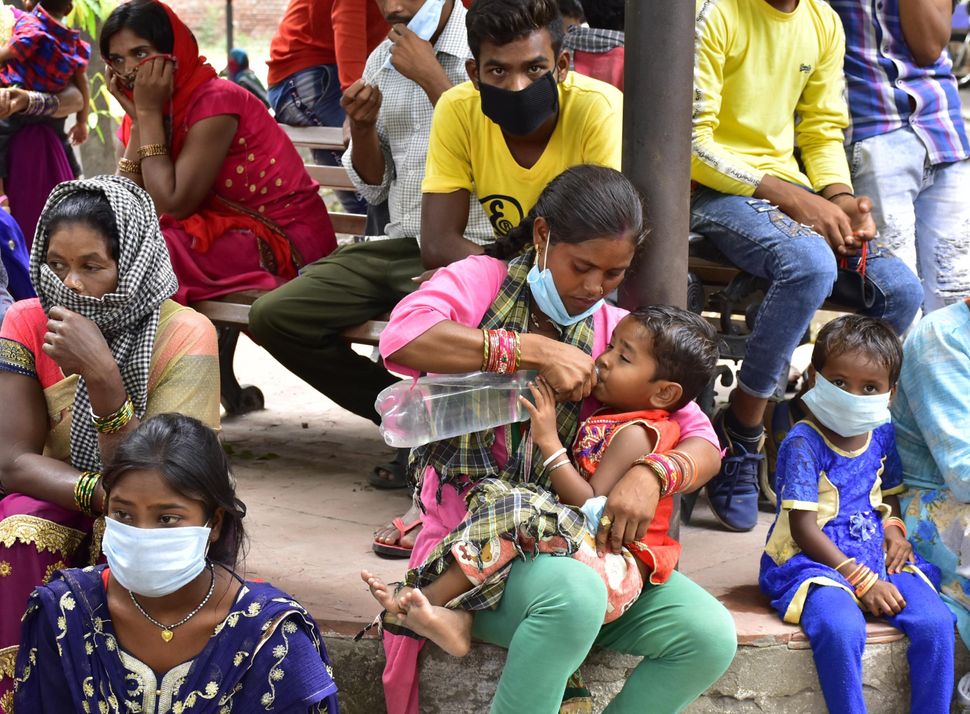 A woman feeds water to her child while stranded migrant workers staged a protest outside Deputy Commissioners residence demanding their return to their homes in another state amid the lockdown, on June 3, 2020 in Amritsar, Punjab.