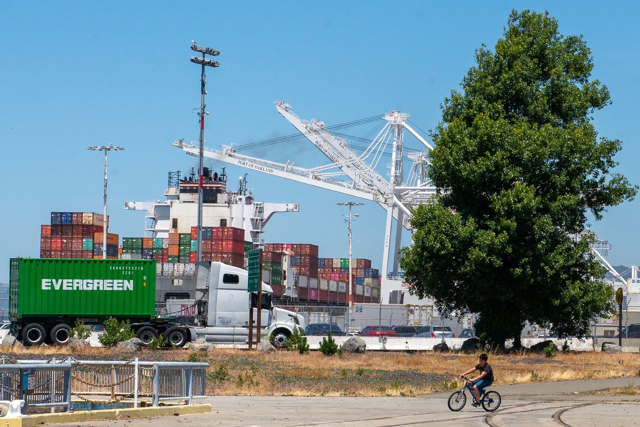 Ken Vasquez, 10, rides his bike at Middle Harbor Shoreline Park while shipping trucks haul freight at the Port of Oakland. Nearly a quarter of middle school students in West Oakland have asthma or other breathing problems.