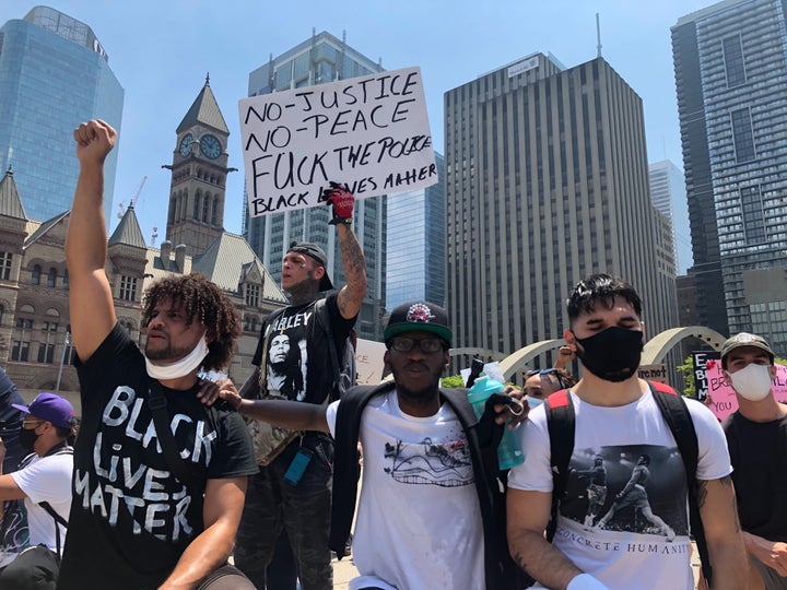 Ashton Forever, left, raises a fist at Toronto's March For Change on Friday.