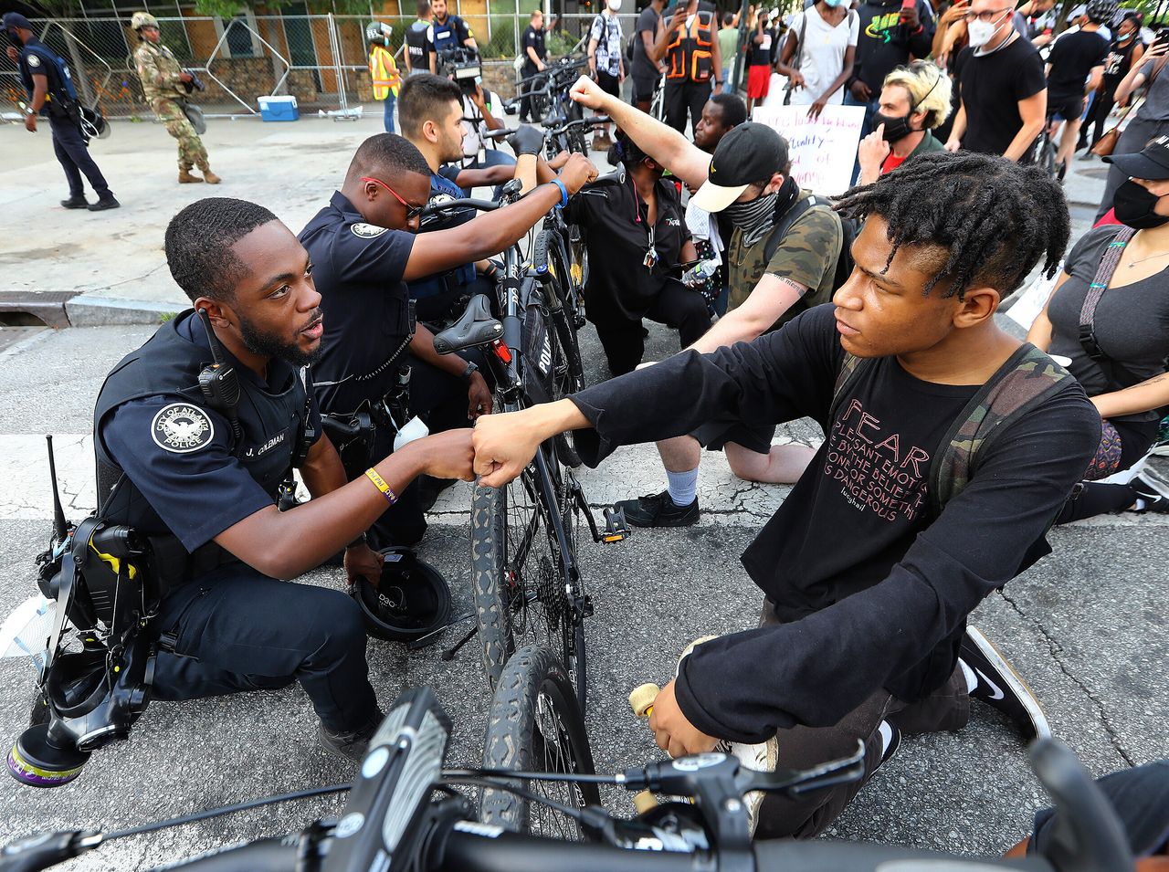 Ο αστυνομικός Τζέι Κόλμαν, γονατίζει και ακουμπάει την φροθιά του με τον διαδηλωτή Ελάιτζα Ράφινγκτον, σε μια συμβολική χειρονομία αλληλεγγύης έξω από το Κέντρο CNN στην Ατλάντα, την Τετάρτη, 3 Ιουνίου.