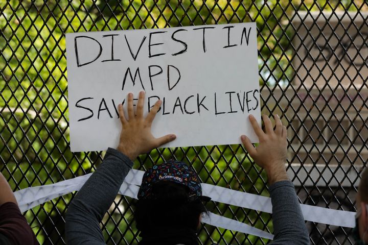 A sign to divest in the police department is held up during a Washington, D.C., protest over the death of George Floyd, an unarmed, handcuffed Black man who died after a white Minneapolis police officer knelt on his neck for nearly nine minutes.
