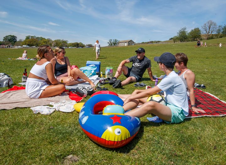 People enjoy the hot weather on the banks of the River Wharfe in Burnsall, Yorkshire, as people flock to parks and beaches with lockdown measures eased.