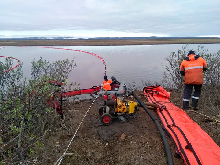 Workers attempt to prevent the spread of the spill.