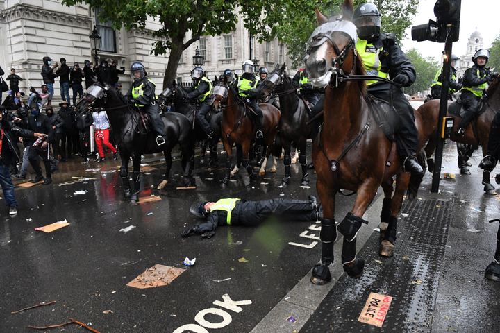 A mounted police officer lays on the road after being unseated from their horse, during a demonstration on Whitehall.