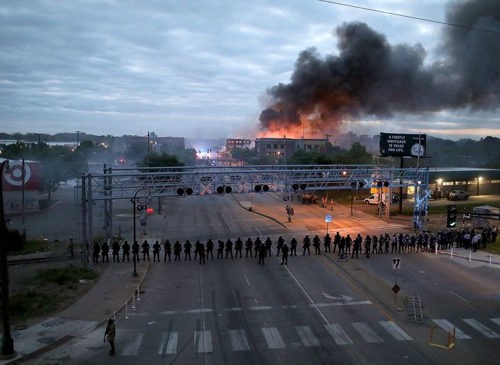 Law enforcement officers stand in formation along Lake Street near Hiawatha Ave. as fires burned after a night of unrest and protests in the death of George Floyd early Friday, May 29, 2020 in Minneapolis. Floyd died after being restrained by Minneapolis police officers on Memorial Day. (David Joles/Star Tribune via AP)