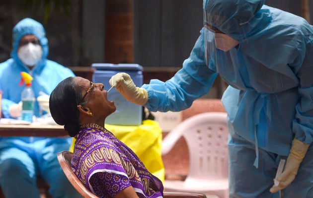 A doctor takes a swab sample of a resident at a coronavirus testing drive inside Dharavi during a government-imposed...