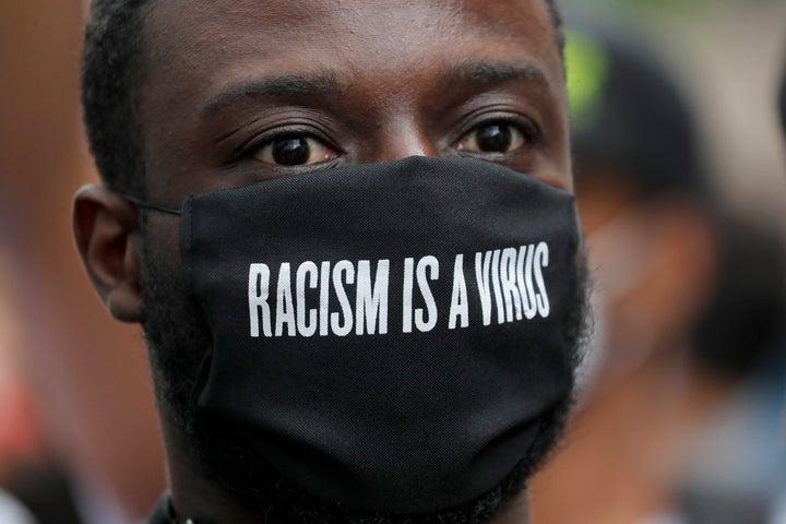 A protester wears a face mask in front of the U.S. embassy, during the Black Lives Matter protest rally in London, Sunday, Ju