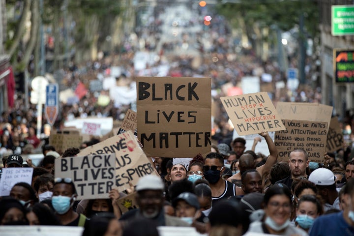 A protester looks up at a sign that reads "Black Lives Matter" in Marseille, southern France, Saturday, June 6, 2020, during a protest against the recent death of George Floyd. (AP Photo/Daniel Cole)