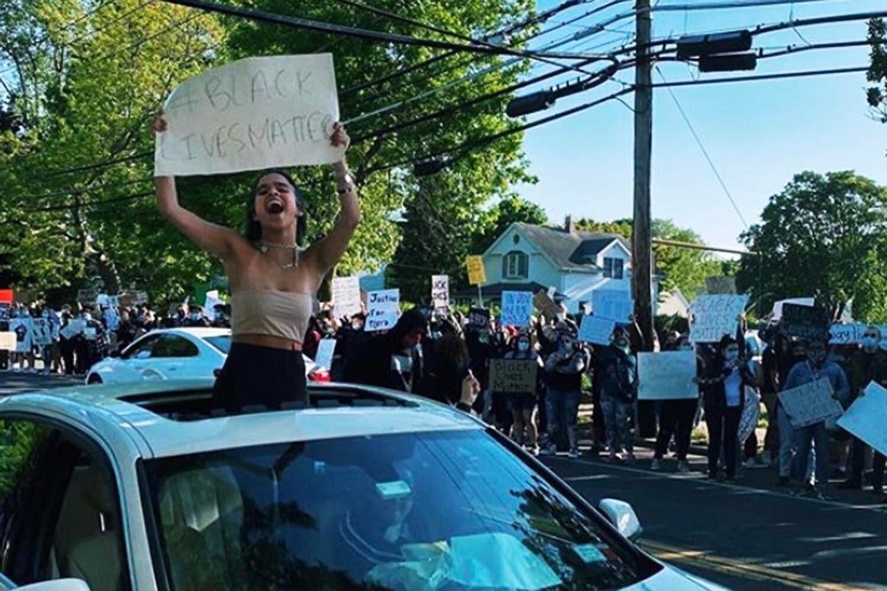 Adriana Alvarez's daughter hoists a sign through their car's sunroof.