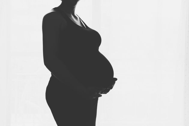 Pregnant woman standing against the window