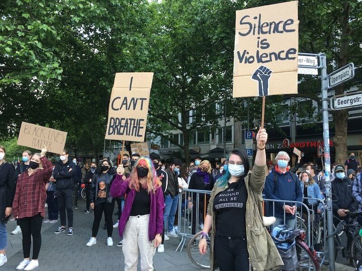 「Silence is violence（沈黙は暴力だ）」を掲げるデモ参加者