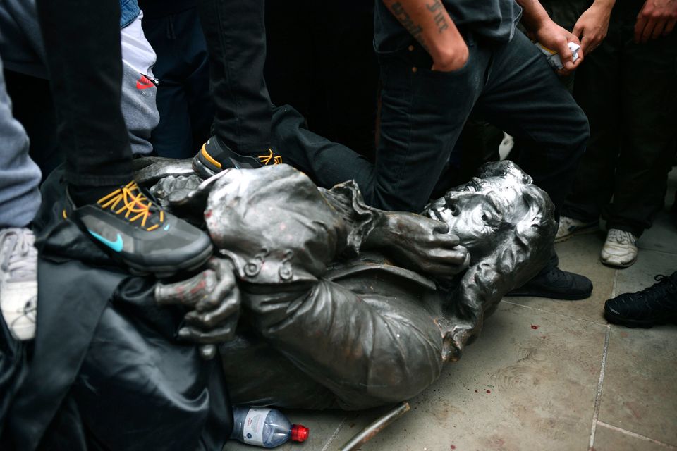 One protester kneels on the neck of Edward Colston, a symbolic gesture referencing the death of George Floyd. 