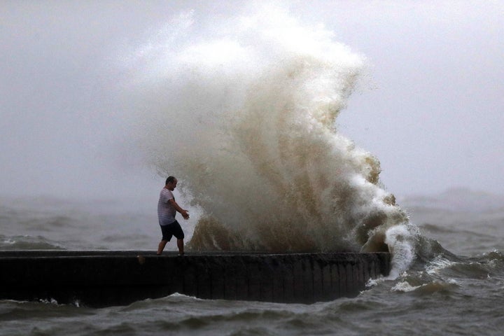 A wave crashes as a man stands on a jetty near Orleans Harbor in Lake Pontchartrain in New Orleans on June 7, 2020, as Tropic