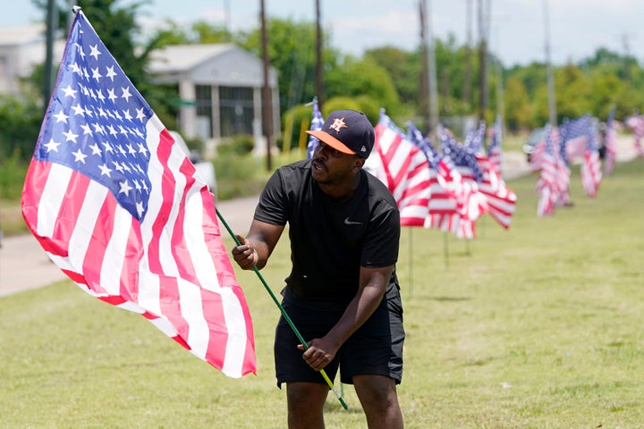 Bryan Smart plants American flags along Hillcroft Ave. as he walks toward The Fountain of Praise church on June 7, 2020, in Houston.