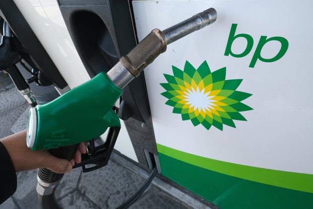 A man holds a gasoline hose beside a BP logo in the Netherlands on April 26, 2020. Major companies...