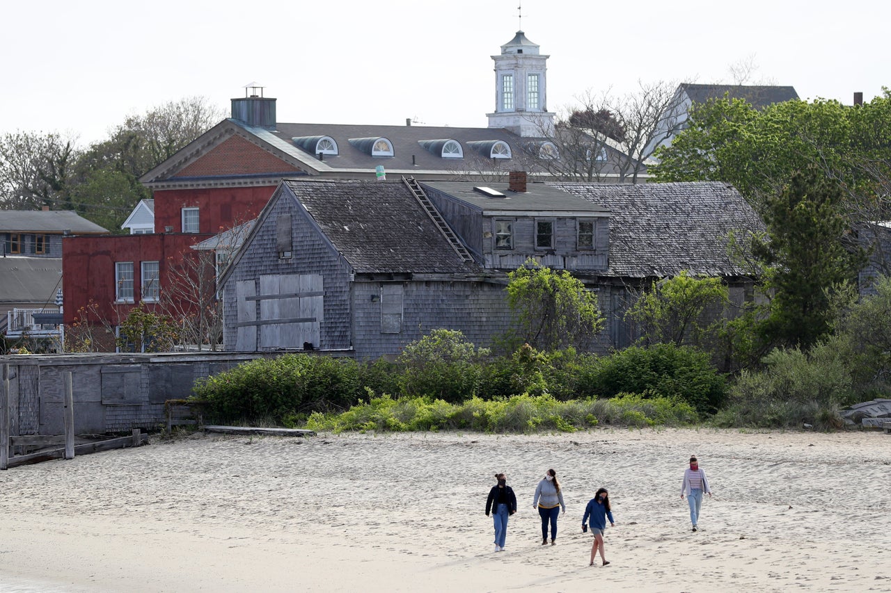 People walk on the beach at Provincetown Harbor on May 25. The country's unofficial LGBTQ summer playground faces a greater challenge this year because of the coronavirus.