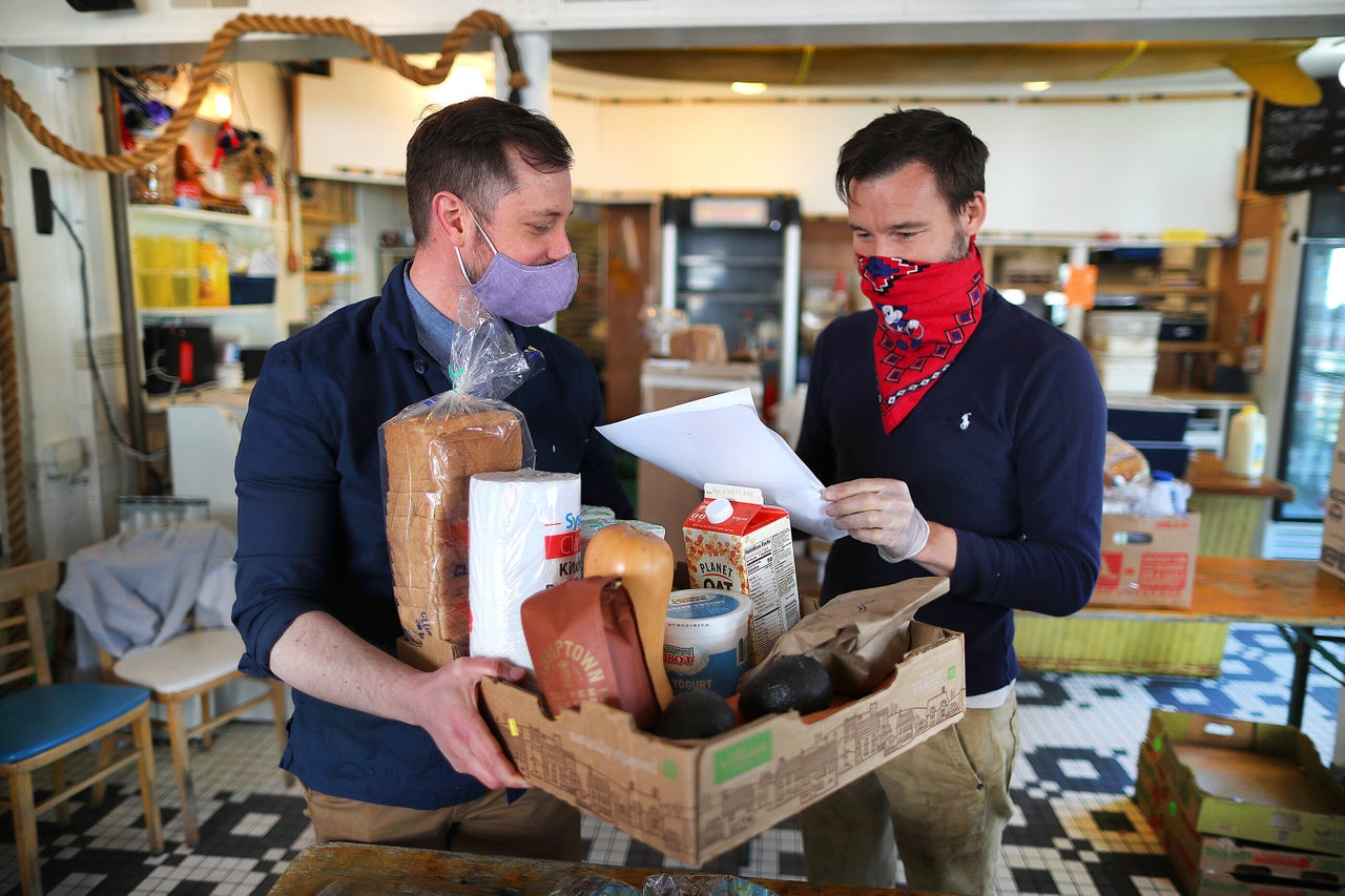 Rob Anderson (left), co-owner of the Canteen, and his partner and co-owner Loïc Rossignon make up a grocery order for delivery inside their Provincetown restaurant on May 13.