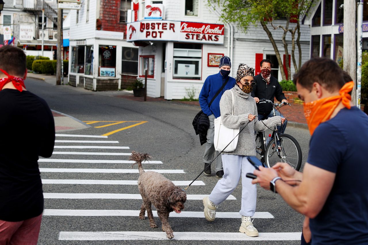 People wearing face masks walk down Commercial Street on May 25.