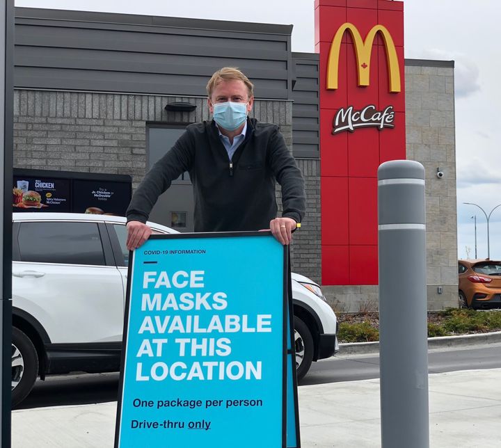 Alberta Health Minister Tyler Shandro poses with a sign outside of an Alberta McDonald's location.