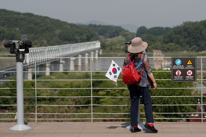 A visitor carrying a South Korean flag uses binoculars to view the northern side at the Imjingak Pavilion in Paju, South Korea, on June 9, 2020.