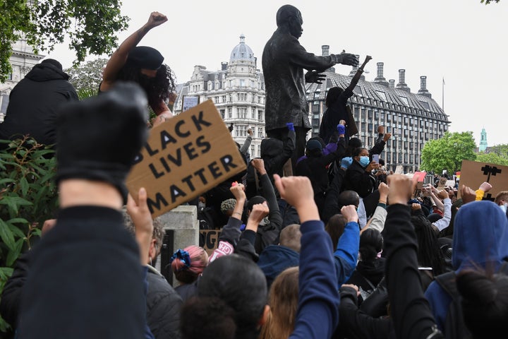 Protesters gather around the Nelson Mandela sculpture in Parliament Square during the Black Lives Matter protest rally in London, Sunday, June 7, 2020, in response to the recent killing of George Floyd by police officers in Minneapolis, USA, that has led to protests in many countries and across the US. (AP Photo/Alberto Pezzali)