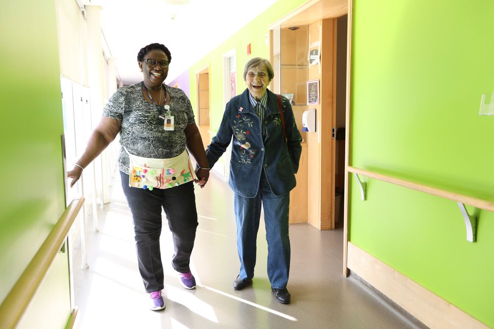 Malton Village resident Inga Cherry walks through the hallway with Geva Lindsay, a personal support worker, at the Mississauga, Ont. home.