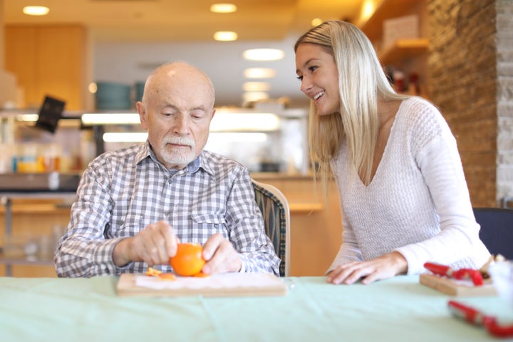 Activation worker Chelsea Martens sits with Piotr (Peter) Wojcik while he peels an orange at Malton Village in Mississauga, Ont.
