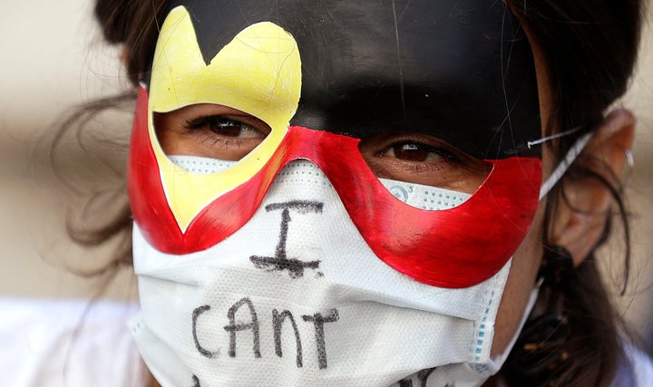 A protester wears a mask as thousands gather at Town Hall in Sydney, Saturday, June 6, 2020, to support the cause of U.S. protests over the death of George Floyd. Black Lives Matter protests across Australia proceeded mostly peacefully as thousands of demonstrators in state capitals honored the memory of Floyd and protested the deaths of indigenous Australians in custody. (AP Photo/Rick Rycroft)