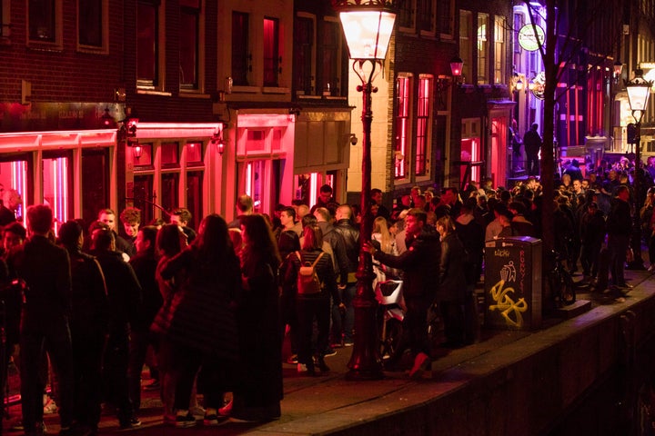 Tourists pack Amsterdam's red-light district. In January, the city banned tours past the windows where sex workers pose to re