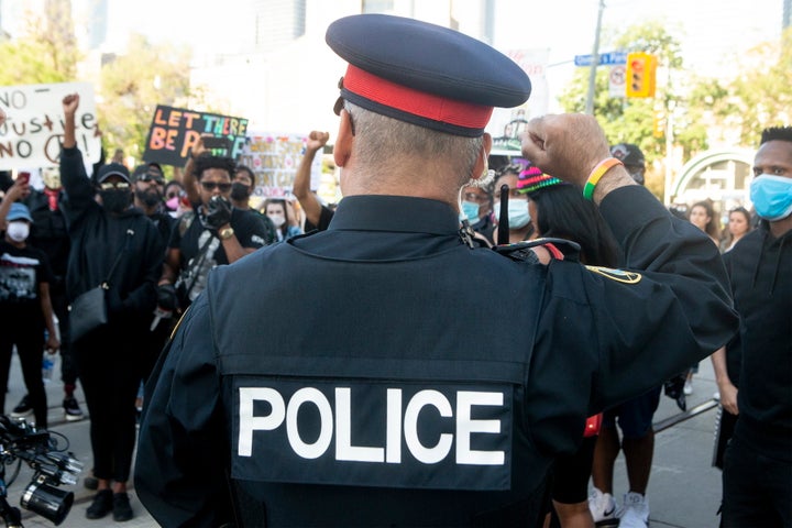 A police officer throws up a fist as protesters march in an anti-racism rally in Toronto on June 6, 2020. 