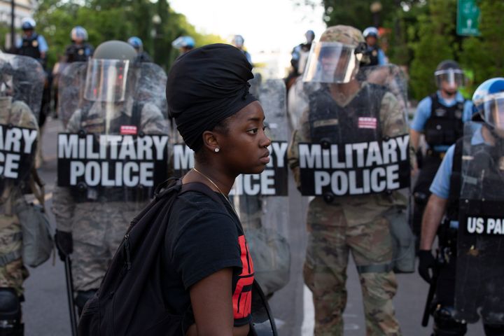 A demonstrator walks in front of a row of military police wearing riot gear as they push back demonstrators outside the White House, on June 1.