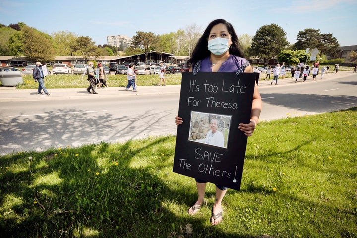 Audrey Da Cruz poses with a picture of her late mother Theresa during a demonstration at Extendicare Guildwood in Scarborough, Ont. on May 26.