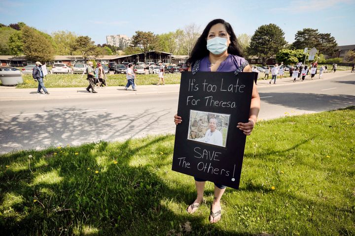 Audrey Da Cruz poses with a picture of her late mother Theresa during a demonstration at Extendicare Guildwood in Scarborough, Ont. on May 26. 